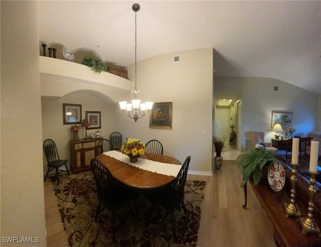 dining space with a chandelier, wood-type flooring, and lofted ceiling