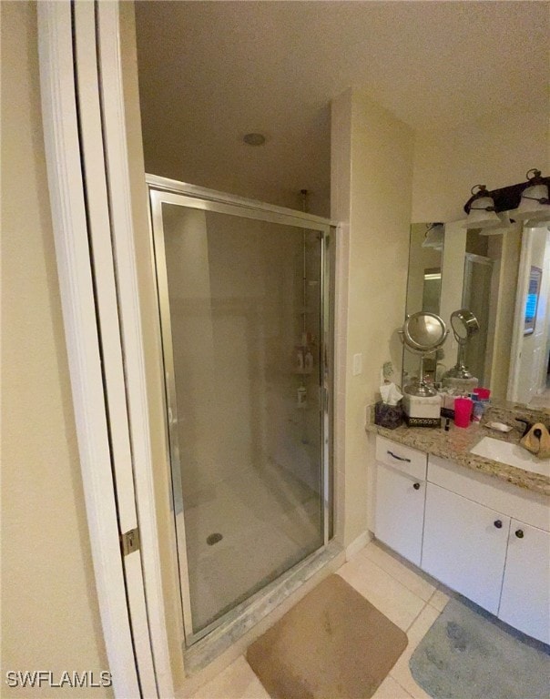 bathroom featuring tile patterned floors, vanity, and a shower with door