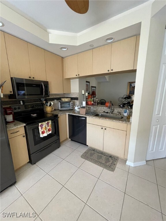 kitchen featuring light tile patterned flooring, light brown cabinets, sink, and black appliances