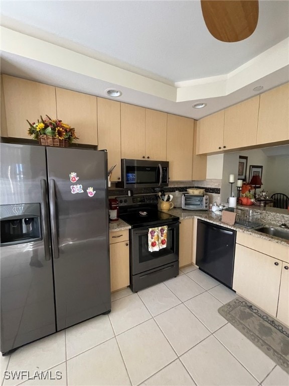 kitchen featuring light tile patterned flooring, light brown cabinets, and black appliances