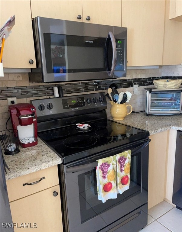 kitchen with black appliances, light stone countertops, light tile patterned floors, and tasteful backsplash