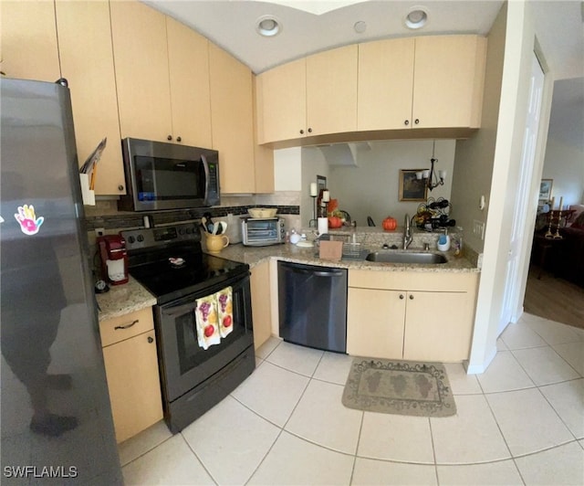 kitchen with light tile patterned flooring, sink, light stone countertops, and black appliances