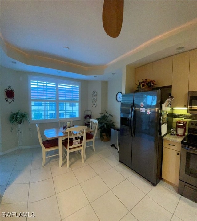 kitchen featuring appliances with stainless steel finishes, a tray ceiling, and light tile patterned flooring