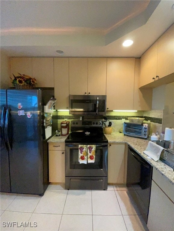 kitchen featuring black appliances, light stone counters, and light tile patterned floors