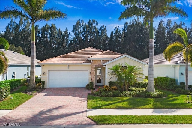 view of front of property featuring decorative driveway, a front yard, an attached garage, and a tile roof