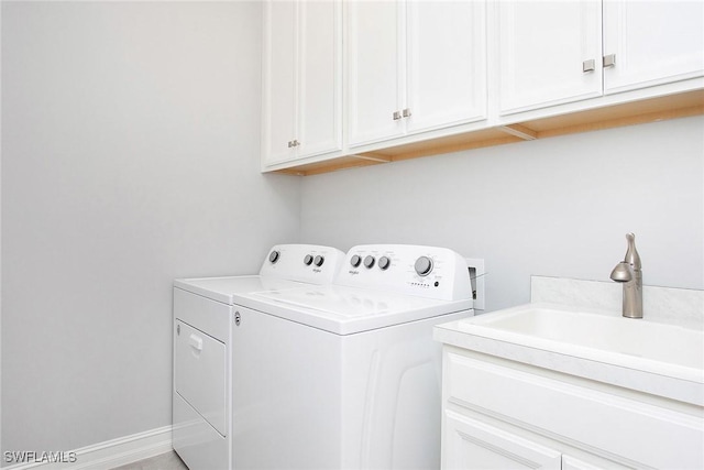 clothes washing area featuring washer and clothes dryer, cabinet space, baseboards, and a sink