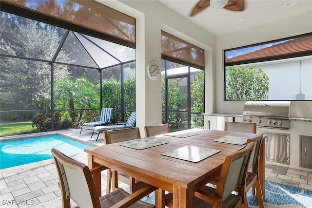 dining area with stone tile floors, a sunroom, and ceiling fan