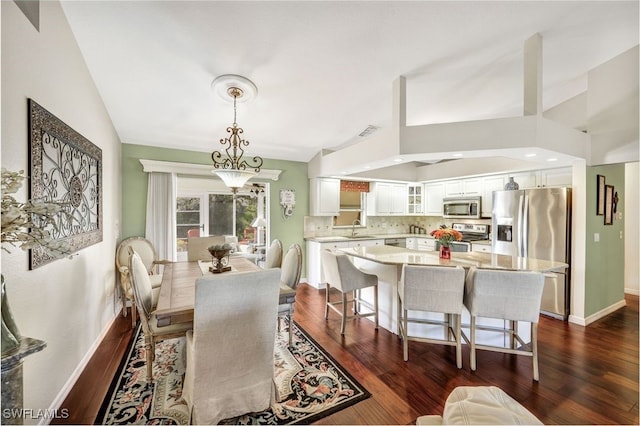 dining area featuring sink, dark wood-type flooring, and vaulted ceiling