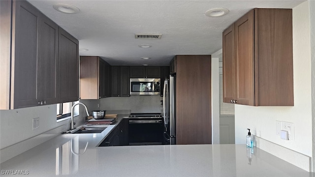 kitchen featuring sink, a textured ceiling, and stainless steel appliances