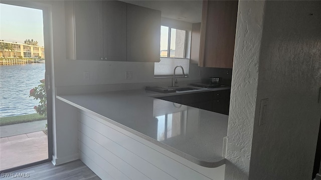 kitchen with sink, a water view, and light wood-type flooring