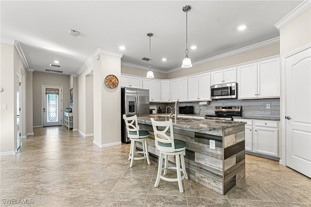 kitchen with a center island with sink, backsplash, appliances with stainless steel finishes, a breakfast bar, and crown molding