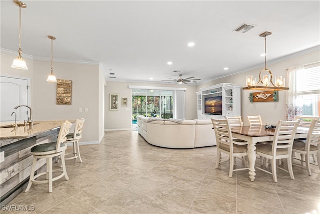 dining area featuring ornamental molding, sink, and ceiling fan with notable chandelier