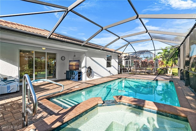 view of pool with a patio, an in ground hot tub, and glass enclosure