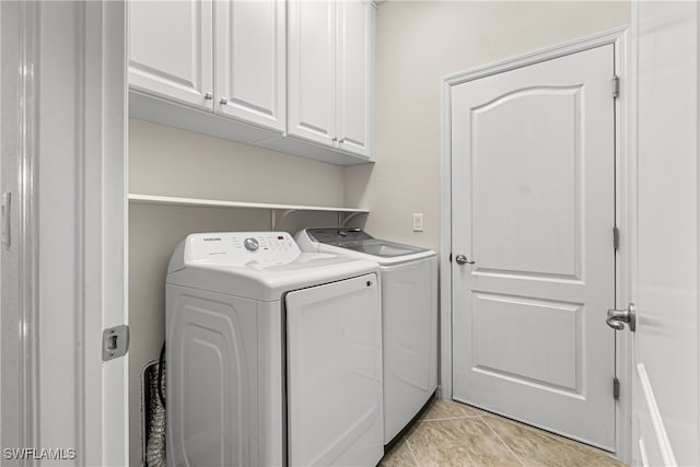 laundry room with washing machine and dryer, light tile patterned floors, and cabinets