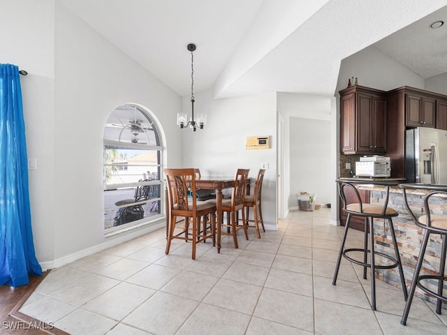 tiled dining area with lofted ceiling and ceiling fan with notable chandelier