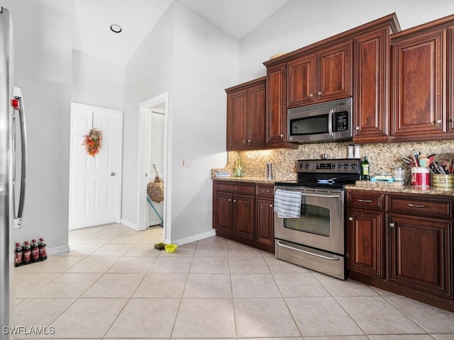 kitchen featuring decorative backsplash, appliances with stainless steel finishes, high vaulted ceiling, light tile patterned flooring, and light stone counters