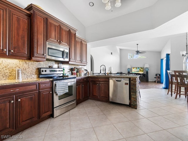 kitchen with light tile patterned floors, light stone countertops, sink, ceiling fan with notable chandelier, and stainless steel appliances