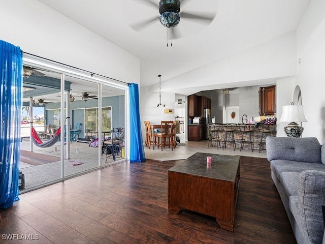 living room featuring dark wood-type flooring, ceiling fan, and high vaulted ceiling