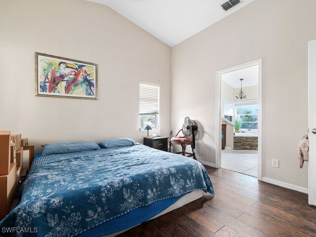 bedroom featuring lofted ceiling, ensuite bathroom, multiple windows, and wood-type flooring