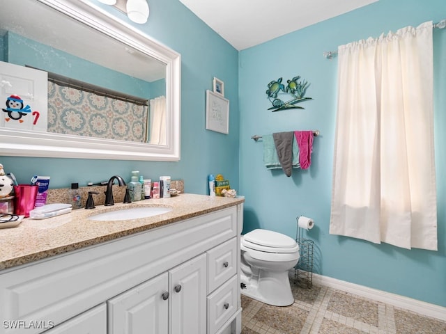 bathroom with toilet, vanity, and tile patterned flooring