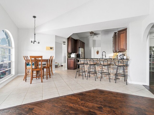 dining space with an inviting chandelier, lofted ceiling, sink, and light wood-type flooring