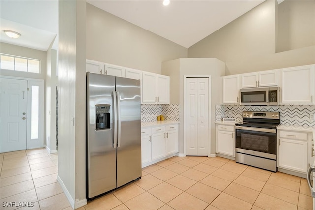 kitchen featuring backsplash, stainless steel appliances, white cabinets, high vaulted ceiling, and light tile patterned floors