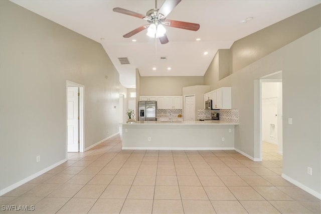 kitchen with kitchen peninsula, white cabinets, stainless steel appliances, and light tile patterned floors