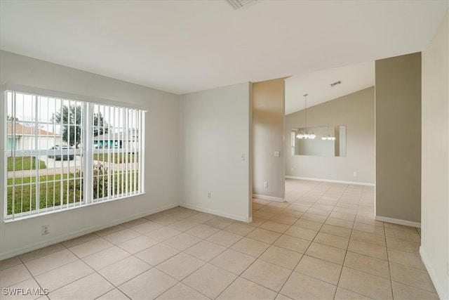 empty room featuring a chandelier, vaulted ceiling, and light tile patterned floors