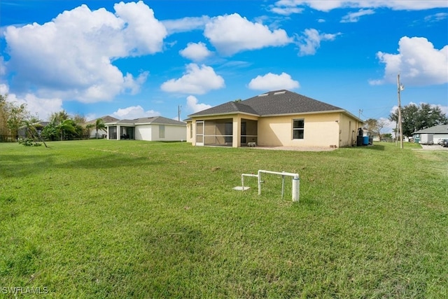 rear view of property featuring a yard and a sunroom