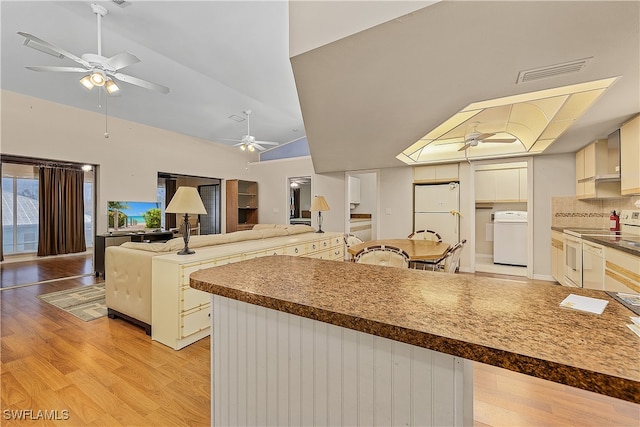 kitchen featuring light hardwood / wood-style floors, tasteful backsplash, washer / clothes dryer, white appliances, and lofted ceiling