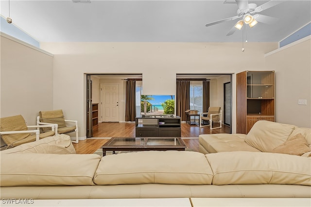 living room with hardwood / wood-style floors, ceiling fan, and vaulted ceiling