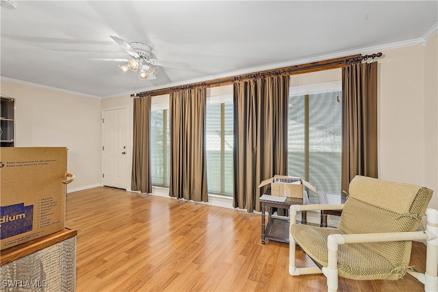 living area with ornamental molding, hardwood / wood-style flooring, and ceiling fan