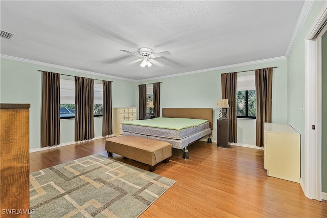 bedroom featuring a textured ceiling, light hardwood / wood-style floors, ceiling fan, and crown molding