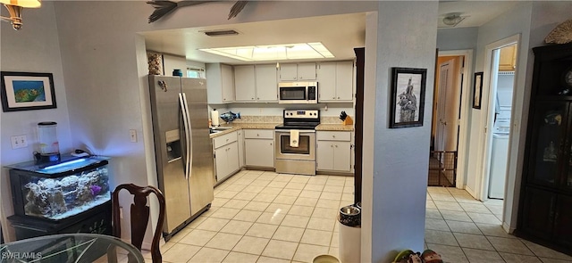 kitchen with white cabinets, light tile patterned floors, and stainless steel appliances