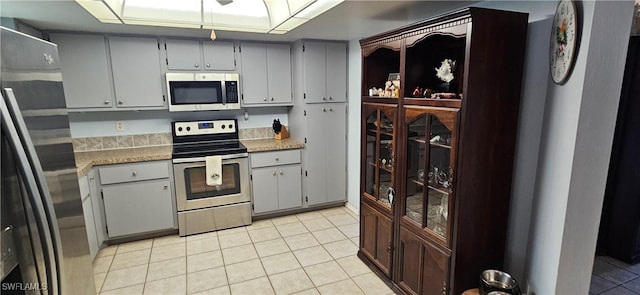 kitchen featuring gray cabinets, light tile patterned floors, and stainless steel appliances