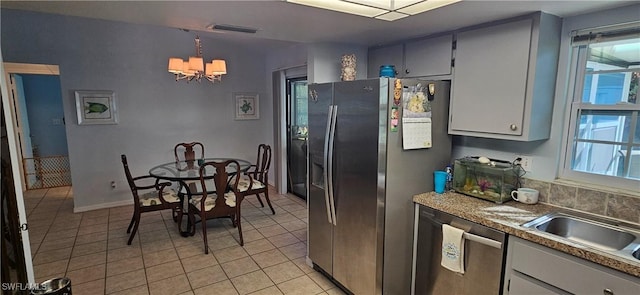 kitchen featuring a chandelier, appliances with stainless steel finishes, a healthy amount of sunlight, and light tile patterned flooring