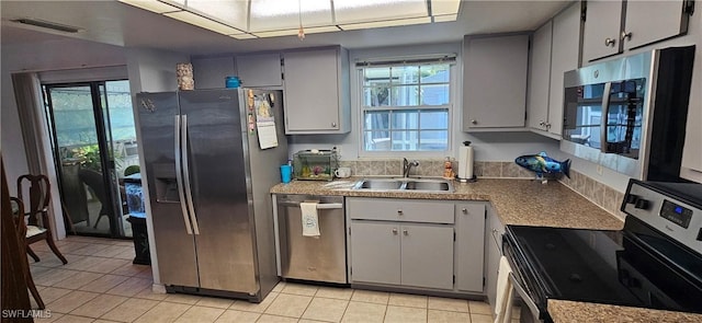 kitchen with plenty of natural light, sink, light tile patterned floors, and stainless steel appliances