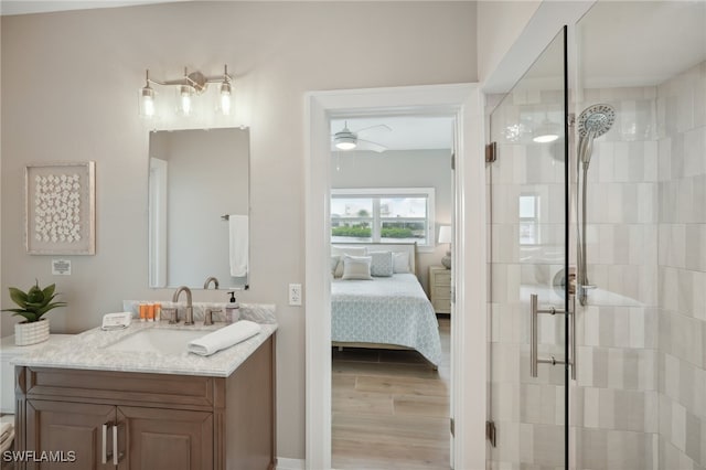 bathroom with a shower with door, ceiling fan, wood-type flooring, and vanity