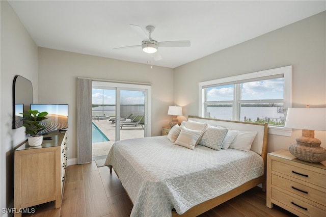 bedroom featuring a water view, access to exterior, light wood-type flooring, and ceiling fan