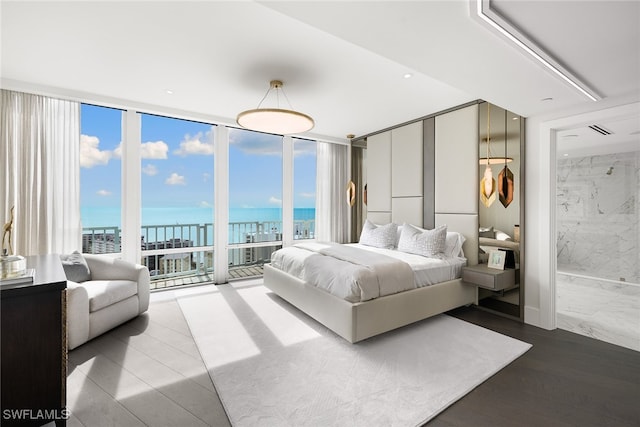 bedroom featuring multiple windows, ensuite bath, hardwood / wood-style flooring, and a water view