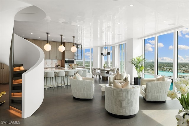 living room with dark wood-type flooring, a water view, and expansive windows