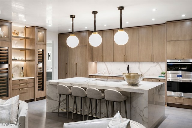 kitchen with a large island, light hardwood / wood-style flooring, pendant lighting, light stone counters, and stainless steel double oven