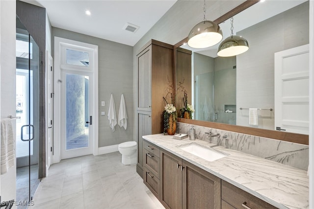 bathroom featuring vanity, a shower with shower door, and toilet