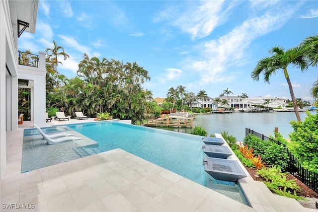 view of swimming pool featuring a patio, a water view, and an outdoor fire pit