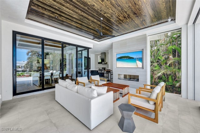 living room featuring a fireplace, wooden ceiling, a raised ceiling, and a wall of windows