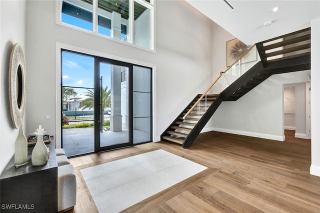 foyer entrance with light hardwood / wood-style flooring and a high ceiling