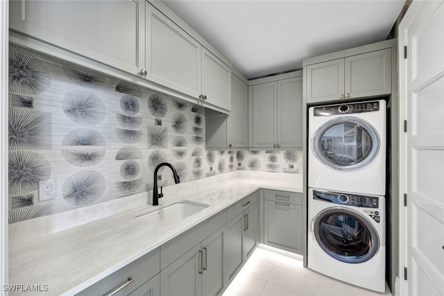 laundry room with sink, cabinets, stacked washer and clothes dryer, and light tile patterned flooring