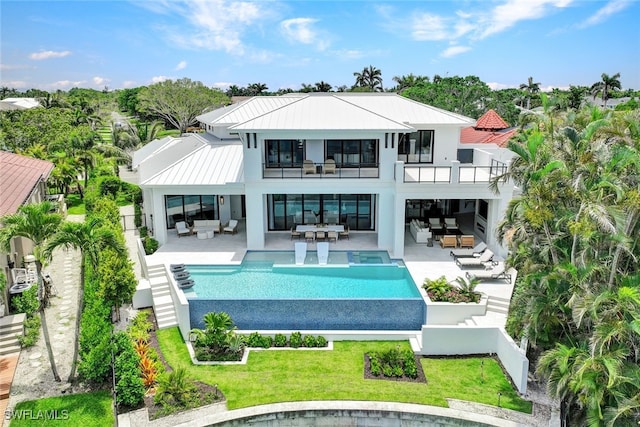 rear view of property featuring an outdoor living space, a lawn, a balcony, and a patio area