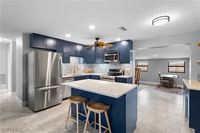 kitchen with decorative backsplash, a breakfast bar area, appliances with stainless steel finishes, sink, and blue cabinets