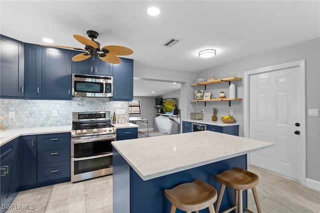 kitchen featuring a breakfast bar area, a center island, blue cabinets, appliances with stainless steel finishes, and tasteful backsplash